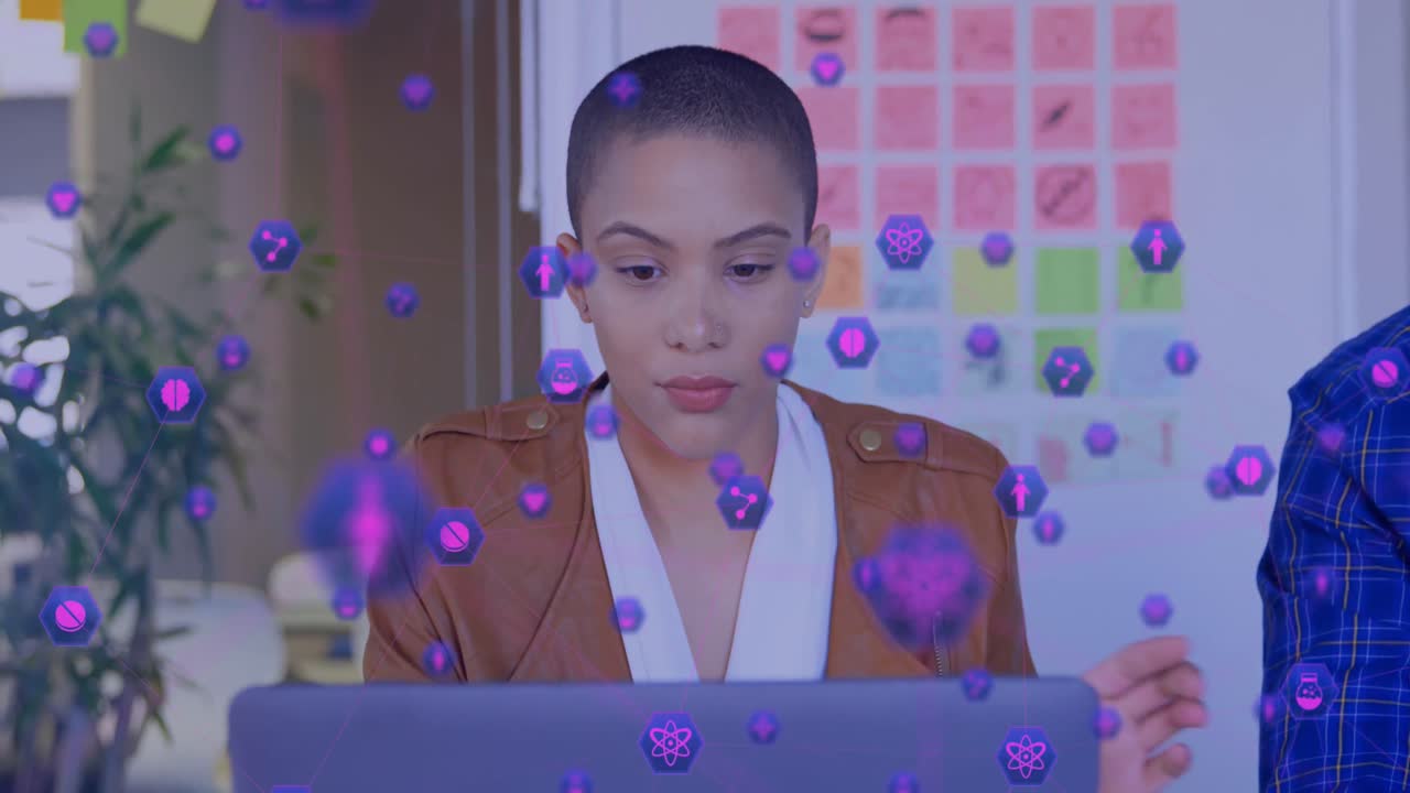 animación de una red de iconos digitales contra una mujer biracial que usa una computadora portátil en la oficina