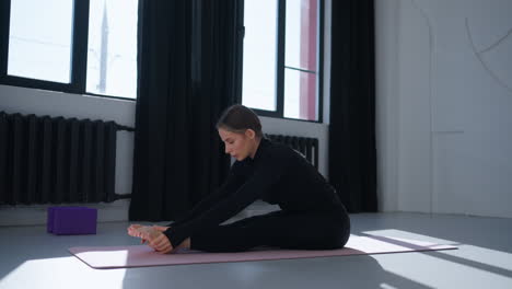 mujer haciendo estiramientos de yoga en una alfombra en un estudio