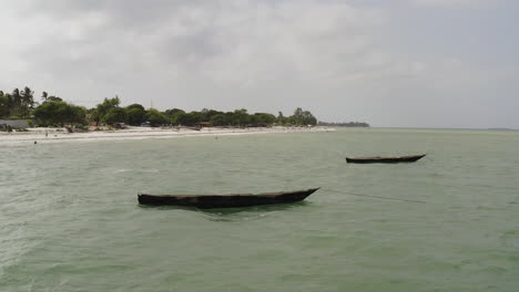 two wooden fishing canoe boats anchored near the beach side near dar es salaam, tanzania