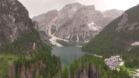 aerial view of lake braies surrounded by rocky mountains and forested valley, italy