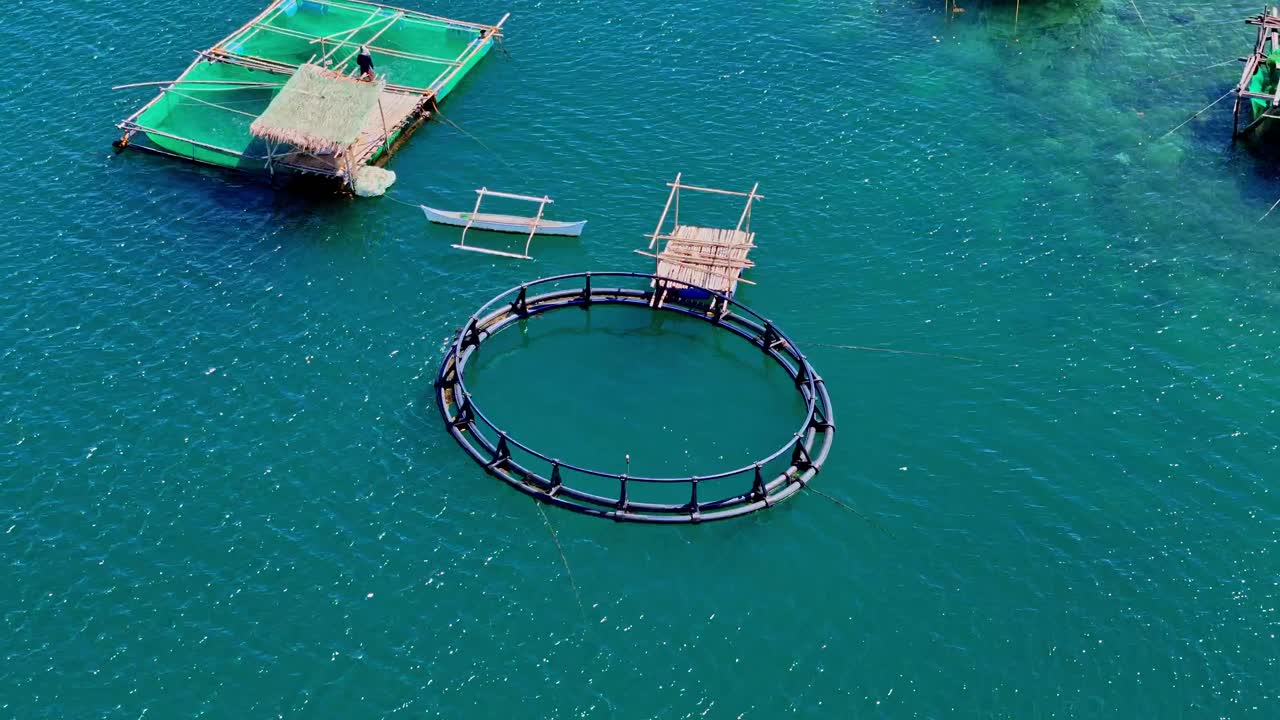 A group of fisherman's huts on stilts, over calm blue ocean water