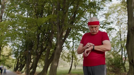 Senior-runner-man-in-park-using-smart-watch,-tracking-distance,-checking-pulse-after-fitness-workout