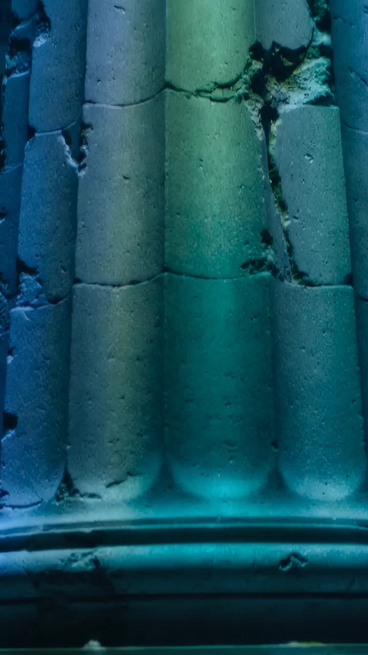 Vertical video: Pulling back camera revealing drum column in hall, exposing cracks and teal light
