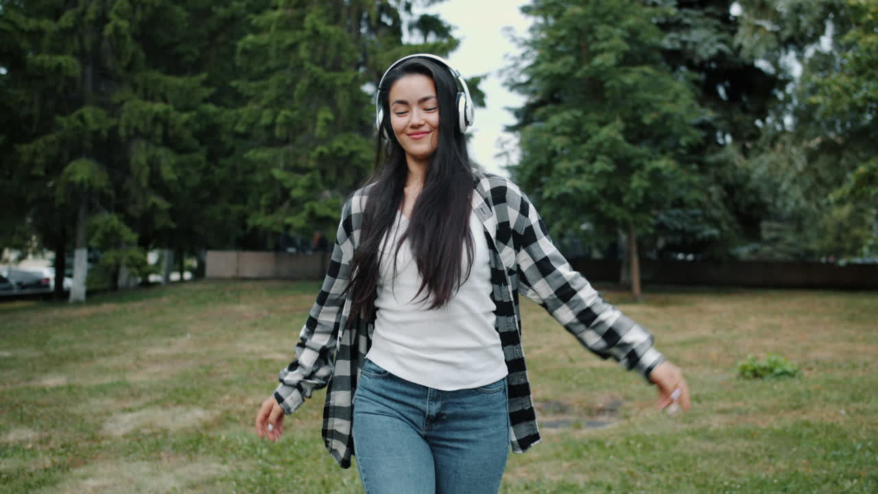 Woman Dancing in Park with Headphones