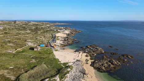 rocky coast of coral strand beach by the calm blue sea in carraroe, county galway, ireland during summer