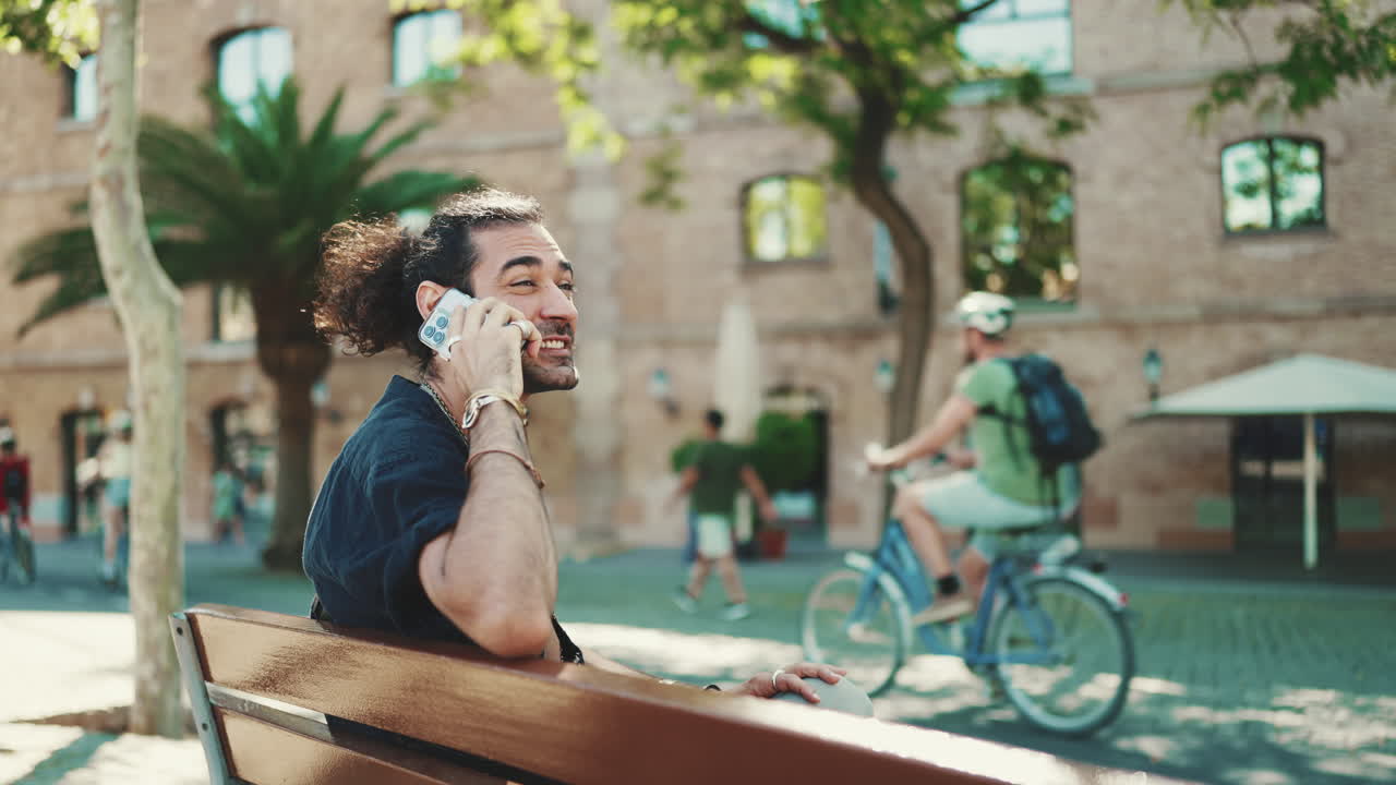 Man talking on the phone while sitting on a bench in an urban environment