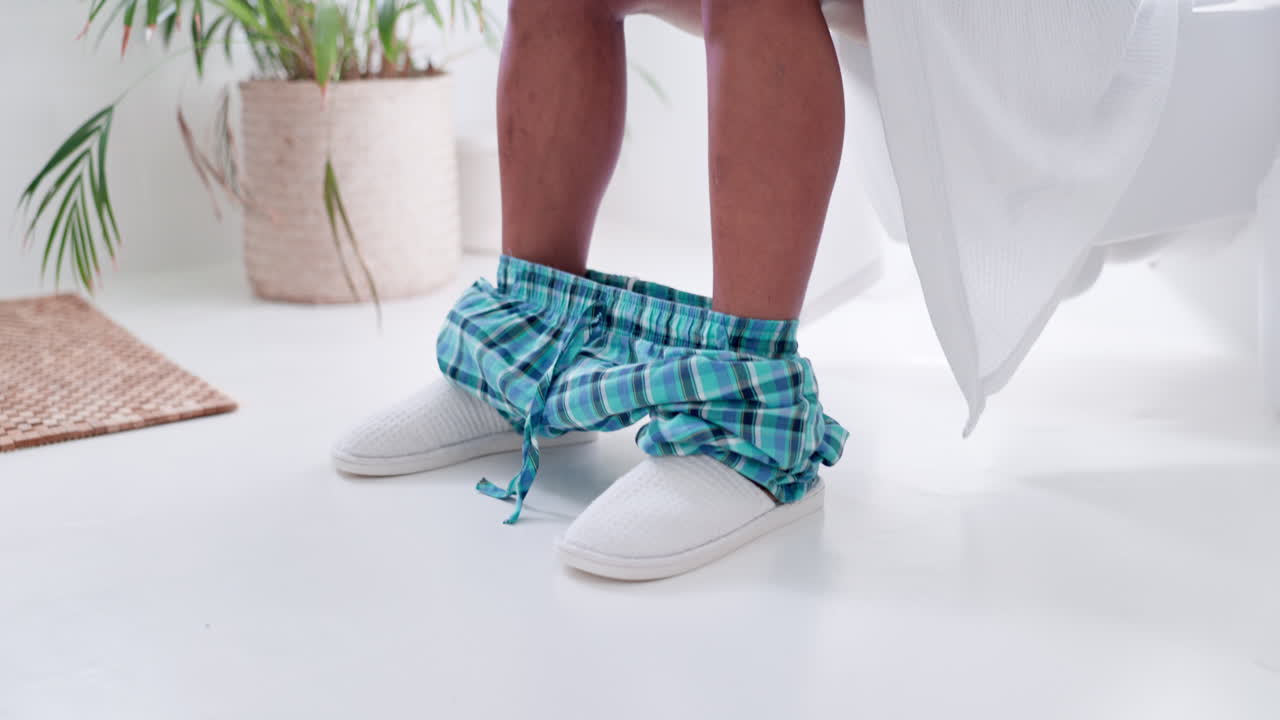 baño, pies y teléfono en el inodoro por la mañana