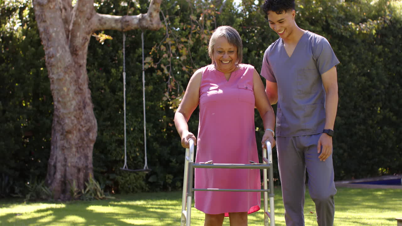 Supporting senior woman with walker, male physiotherapist helping in outdoor therapy session