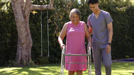 supporting senior woman with walker, male physiotherapist helping in outdoor therapy session