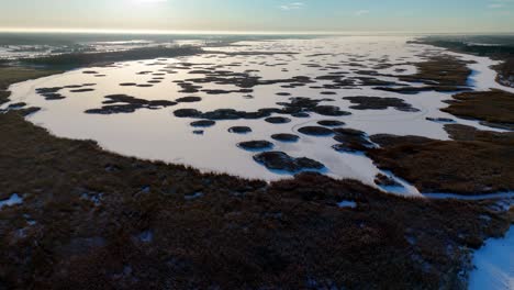 A-large-body-of-water-with-a-lot-of-snow-on-it,-islands-with-grass