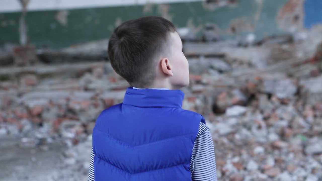 Frightened lonely young boy walk in the ruined house