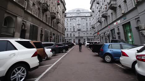 callejón de la ciudad con coches y persona en scooter