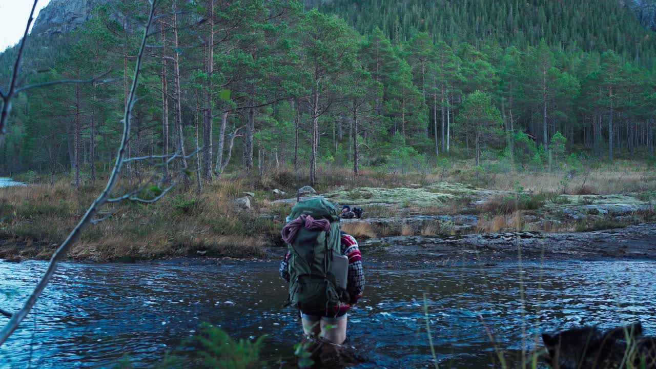 mochilero cruzando el río en una caminata de montaña en el bosque