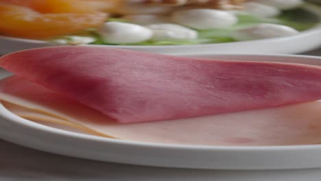 primer plano de jamón en rodajas en un plato blanco