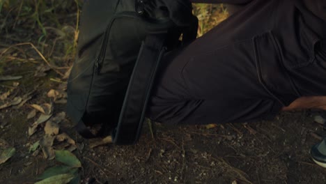 person packing a backpack in the forest
