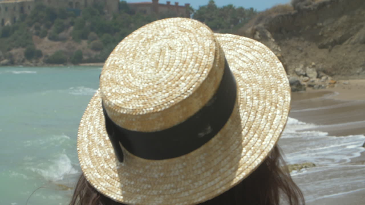 mujer de cabello largo en una playa mirando al océano