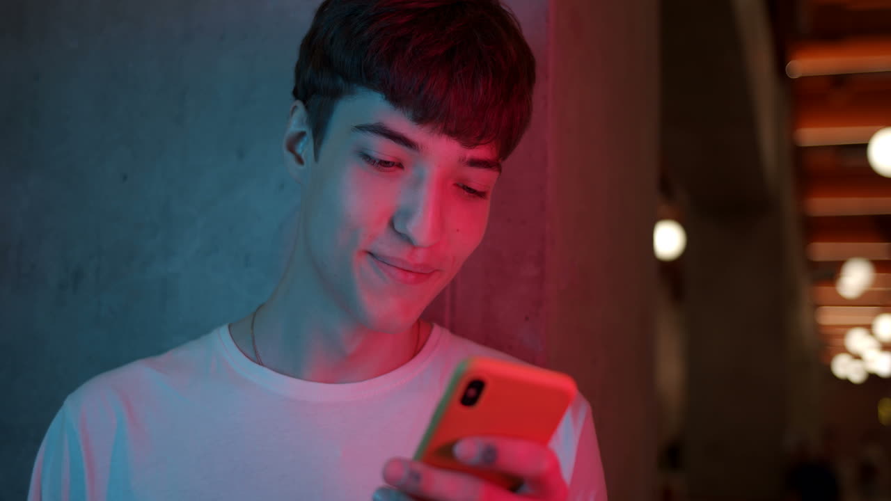 Young Man Using Smartphone in Neon Lighting