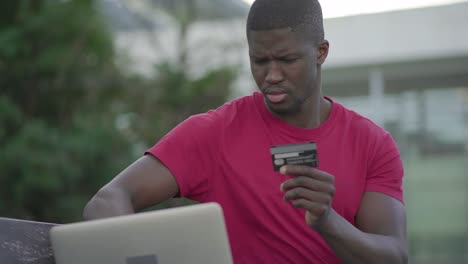 Hombre-Afroamericano-Escribiendo-En-Una-Computadora-Portátil,-Pagando-Con-Tarjeta-De-Crédito