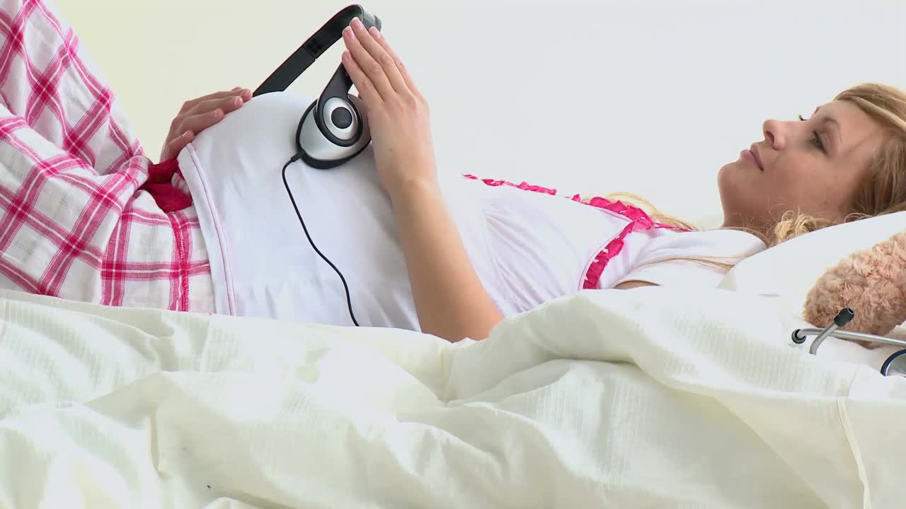 배에 헤드폰을 고 웃는 임신자