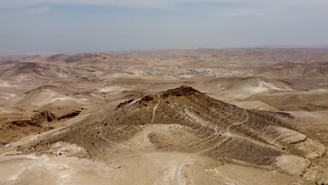 toma aérea lenta y tranquila de una montaña en medio de un desierto vacío y un cielo azul en un día soleado