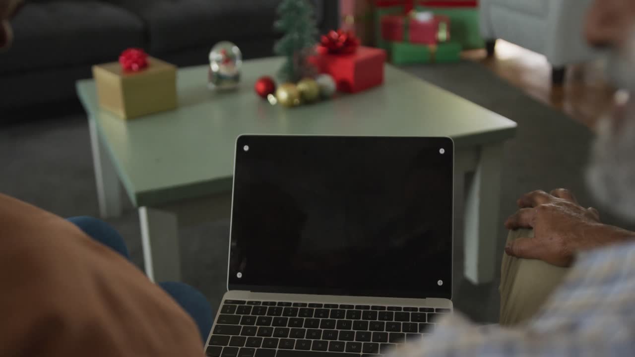 animación de una pareja de ancianos afroamericanos usando una computadora portátil con espacio de copia en la pantalla en el momento de navidad