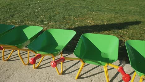 panning shot across row of green wheelbarrows