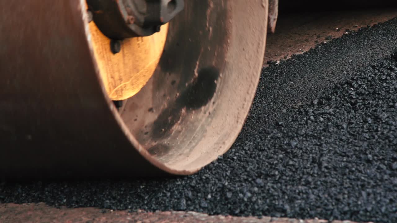 Close up of compactor vehicle is compressing freshly poured hot steaming asphalt