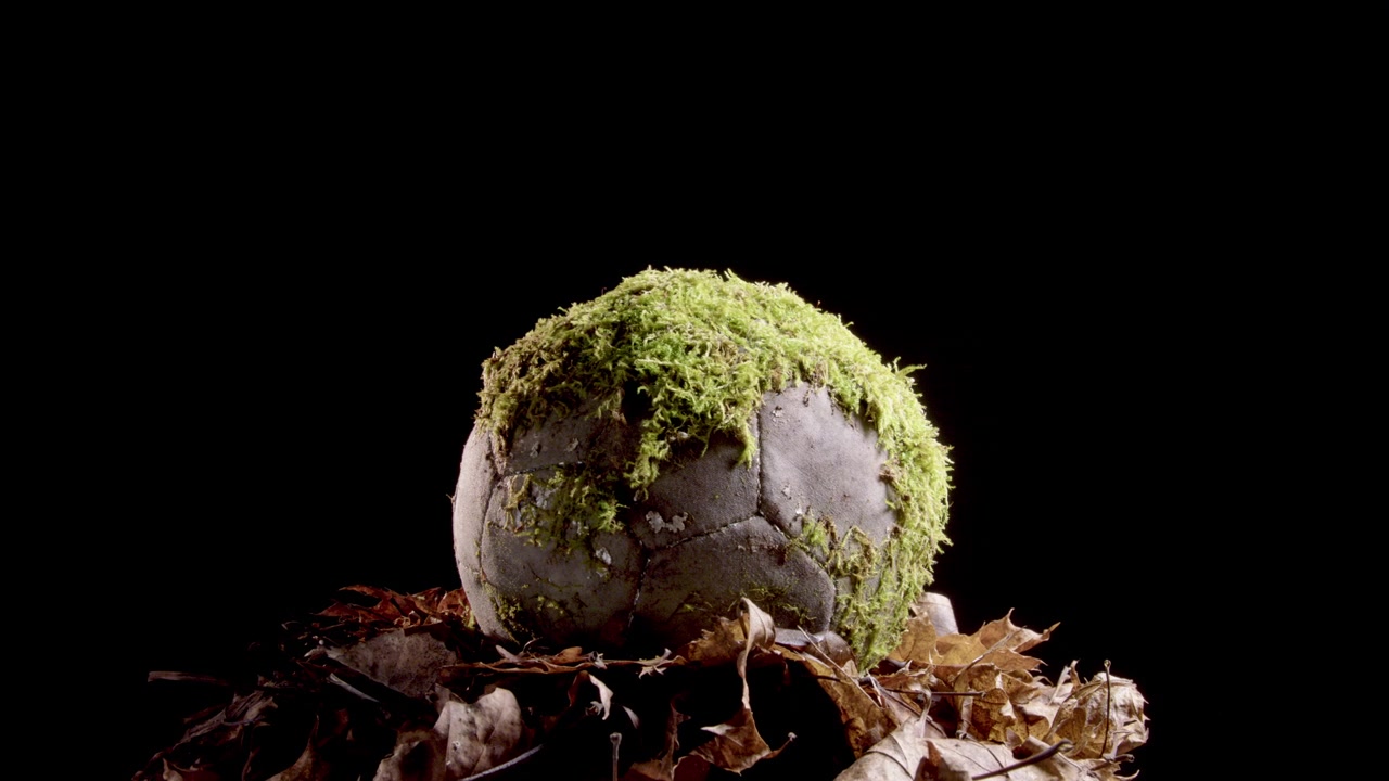 Roterend shot van een zeer oude, met mos bedekte voetbal, studio zwarte achtergrond