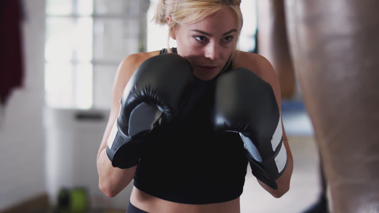 Female Boxer In Gym Training With Old Fashioned Leather Punch Bag