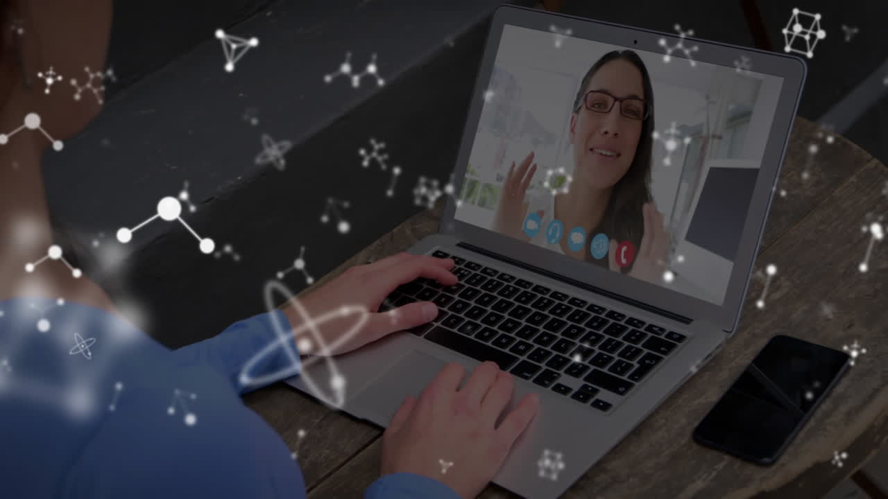 Animation of shapes over caucasian businesswoman having laptop video call with colleague