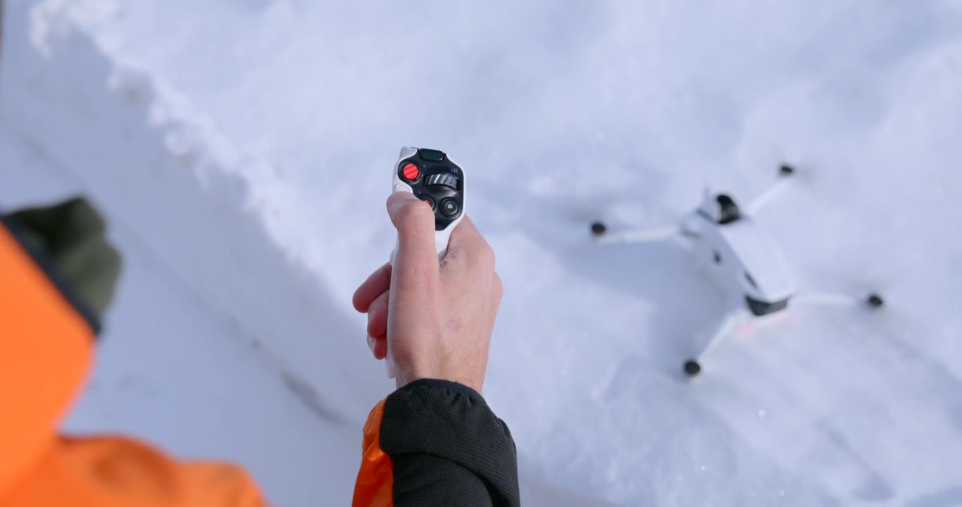 Pilota che aziona un controller di movimento per il decollo di un drone nella neve
