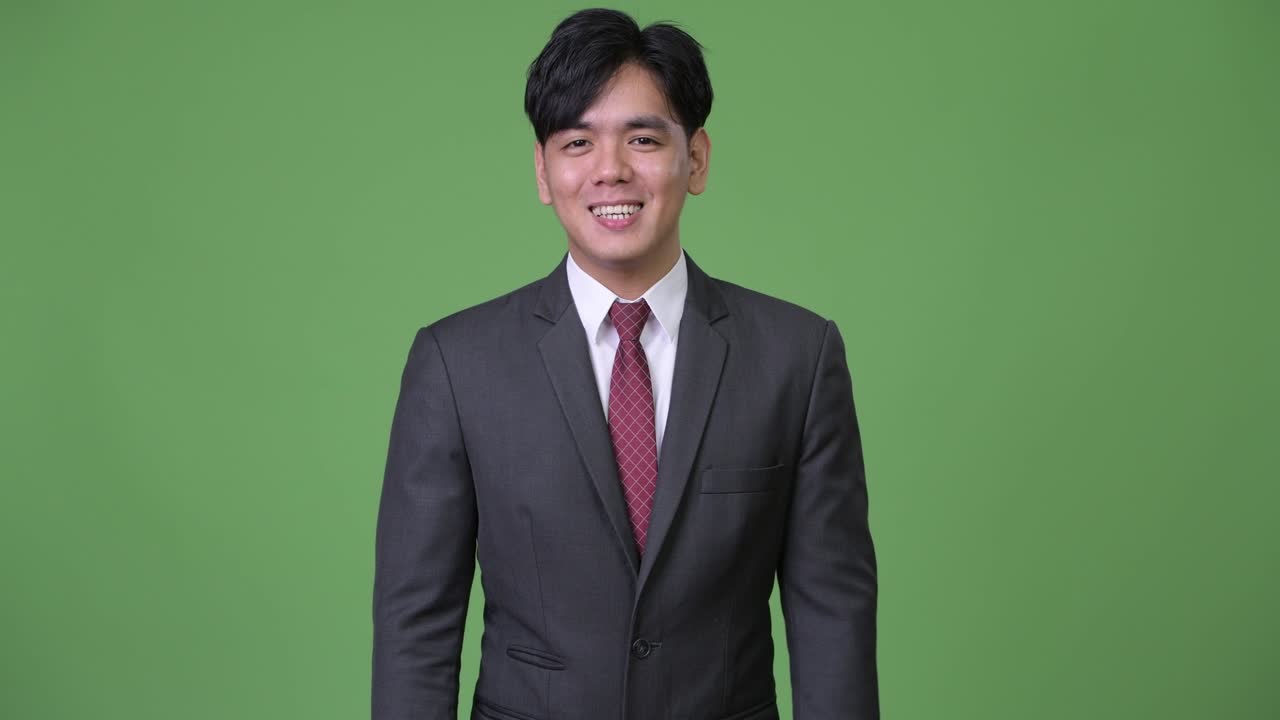 젊은 행복한 아시아 사업가 가 카메라 와 대화 하면서 미소 짓고 있다