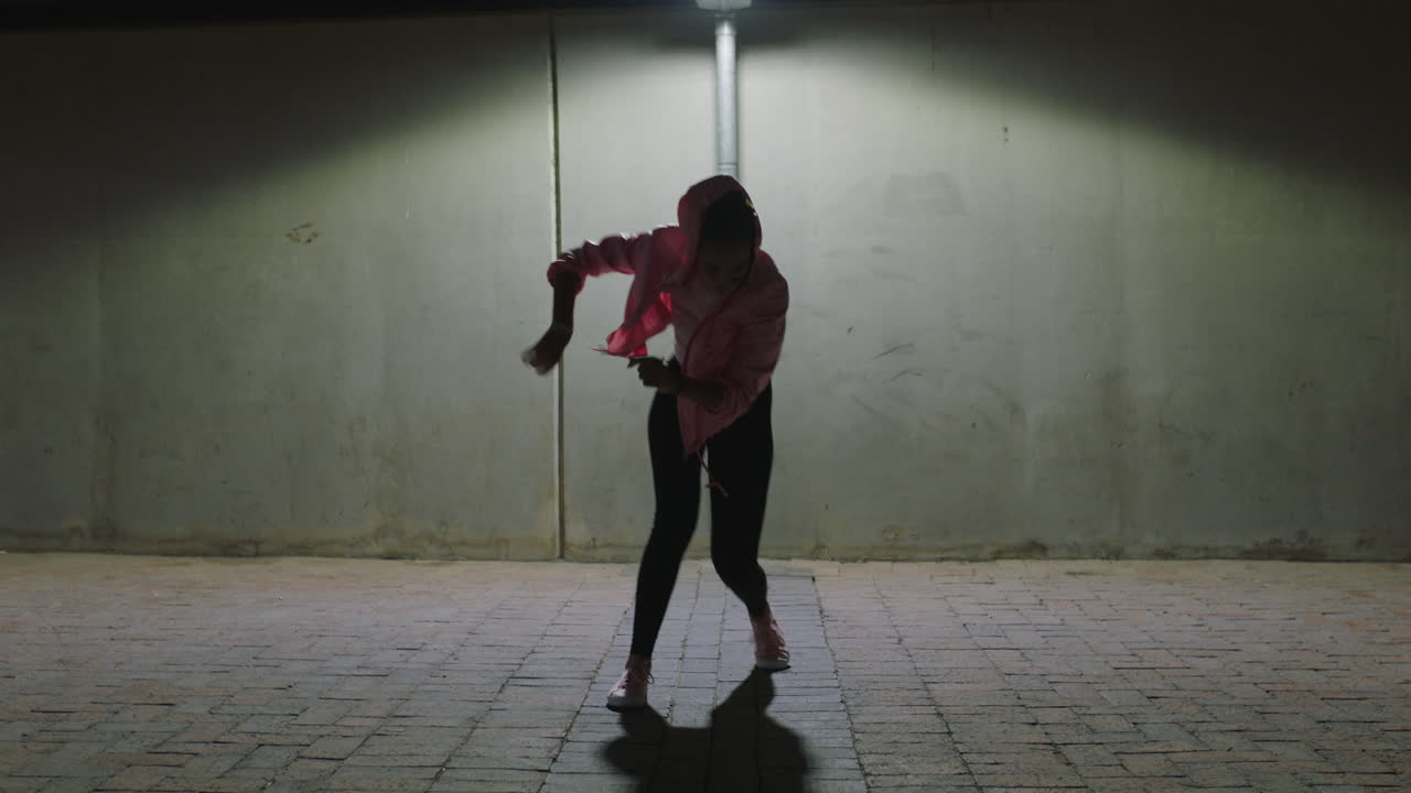 bailarina joven bailarina callejera practicando movimientos de baile moderno de estilo libre bajo la luz de la calle en la ciudad por la noche