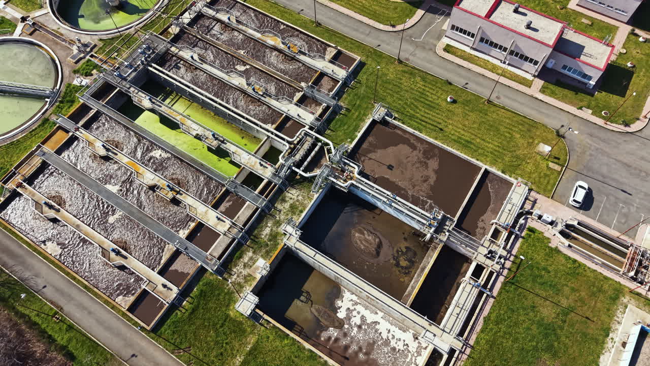 Water treatment facility with multiple tanks and green areas in operation during daylight