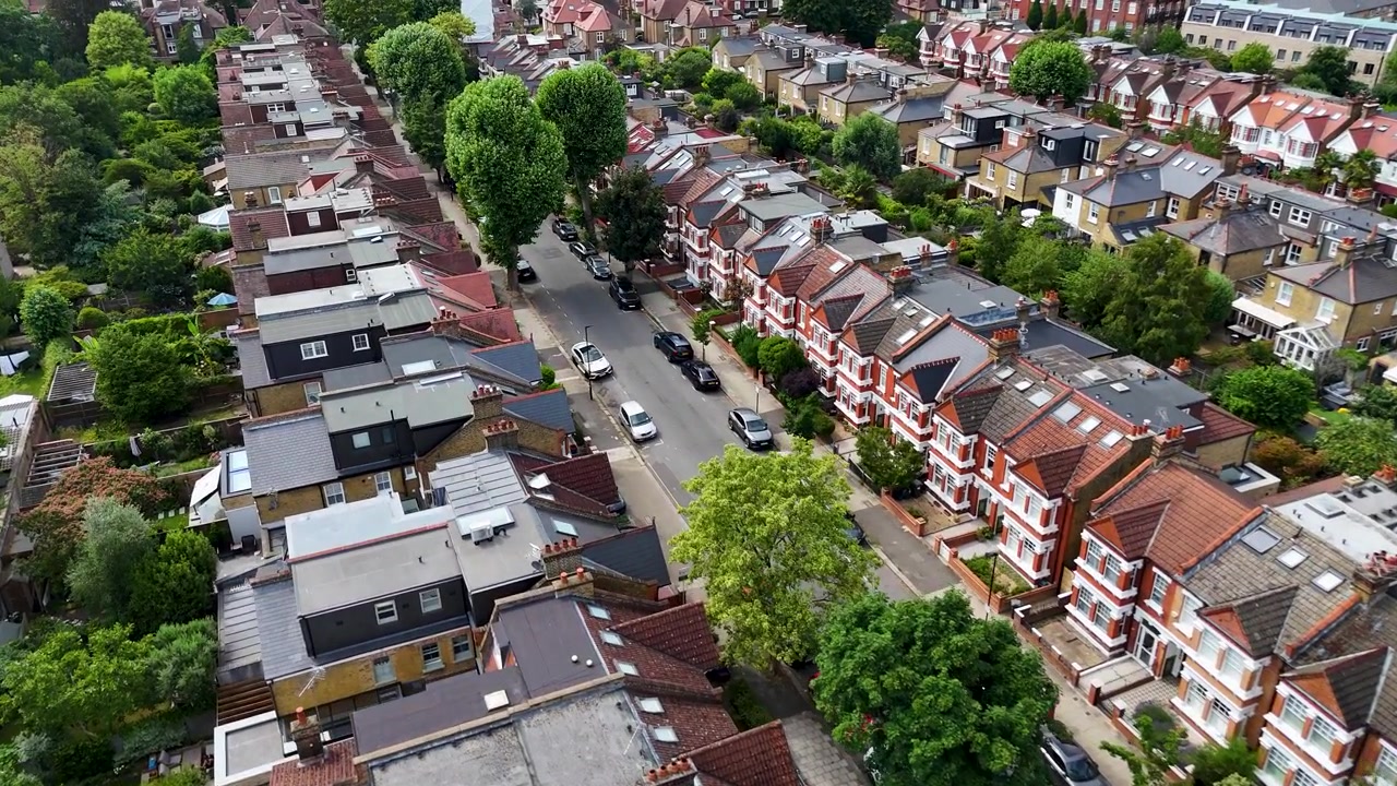File di tetti a terrazza e ampliamenti posteriori si estendono su entrambi i lati di una strada alberata in un denso sobborgo di Londra ovest