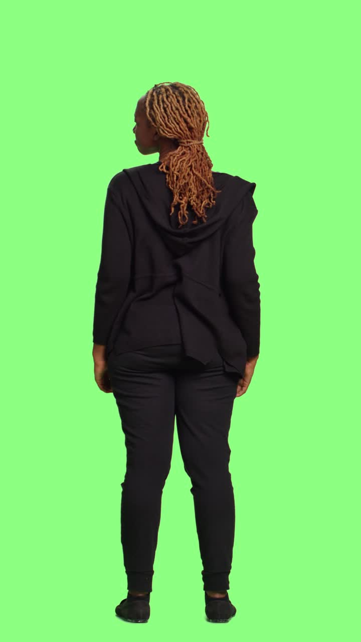 Vertical video: Young adult waiting in line on full body greenscreen backdrop