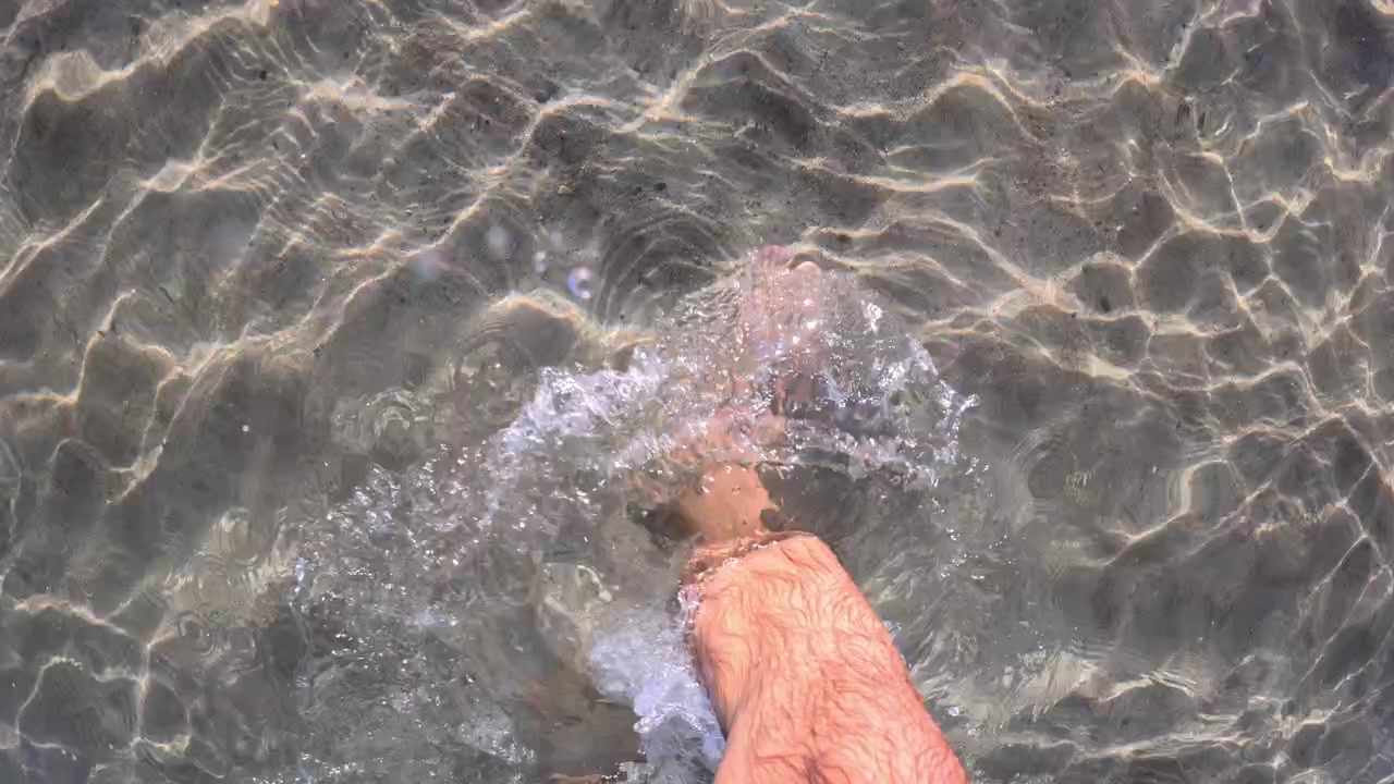 Vista subacquea del piede di un nuotatore sopra sabbia increspata con giochi di luce solare, Golfe-Juan, Francia
