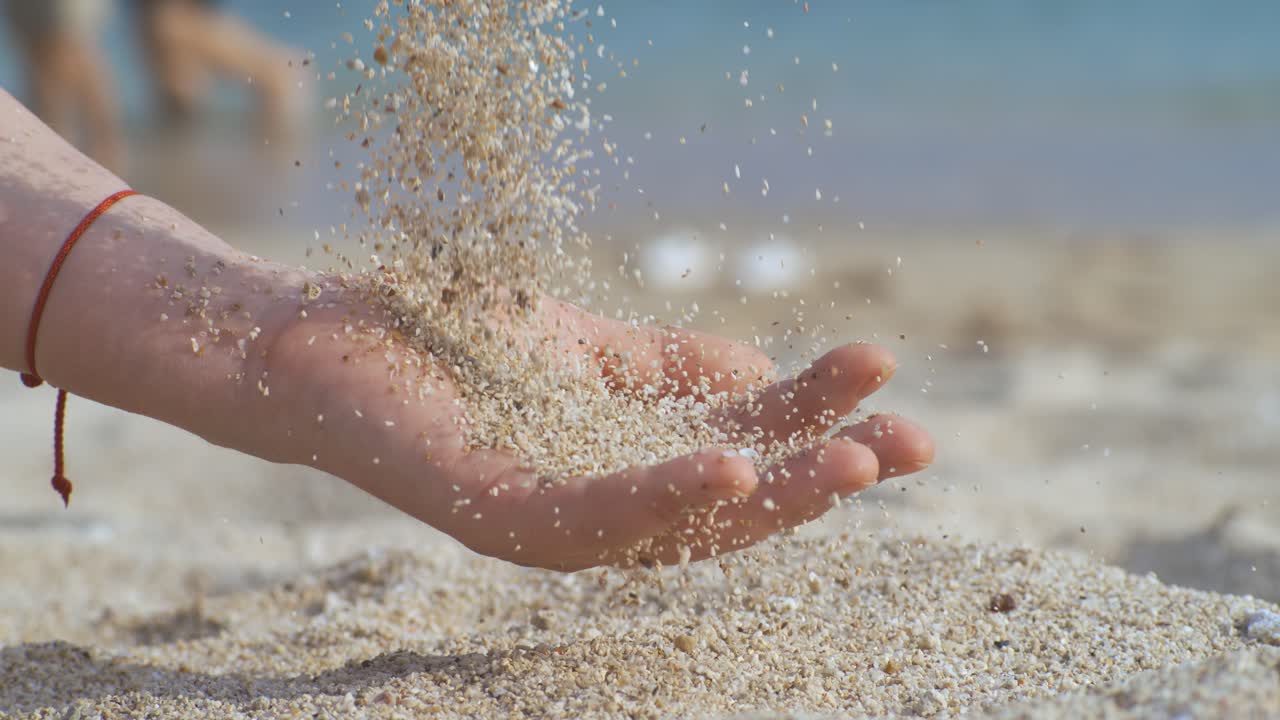 Sand falling from hand in slow motion on a beach. Vacation and travel concept. Shot on super slow motion camera 1000 fps.