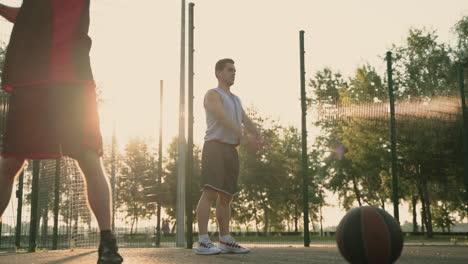 Jugadores-De-Baloncesto-Masculinos-Concentrados-Que-Se-Extienden-En-Una-Cancha-De-Baloncesto-Al-Aire-Libre-Al-Atardecer