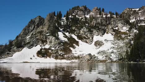 Calm-and-reflective-surface-of-Surprise-Lake-and-mountains-beyond-in-Grand-Teton-National-Park-in-Wyoming-on-a-sunny-summer-day