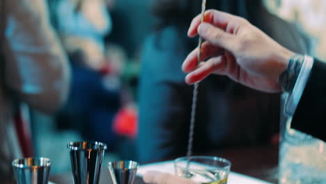 barman shaking alcoholic cocktail in glass with long spoon. barman equipment