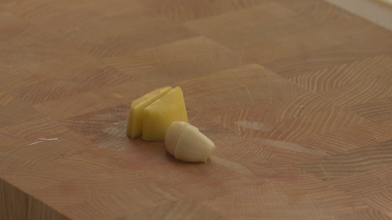 putting peeled ginger on teh cutting board with garlic clove