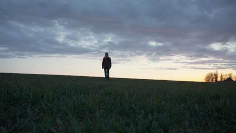 Niña-Caminando-Por-Un-Campo-De-Hierba-Al-Atardecer