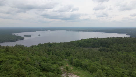 ascending aerial shot over forest covered mountains on edge of lake. calabogie ski hill. ontario canada