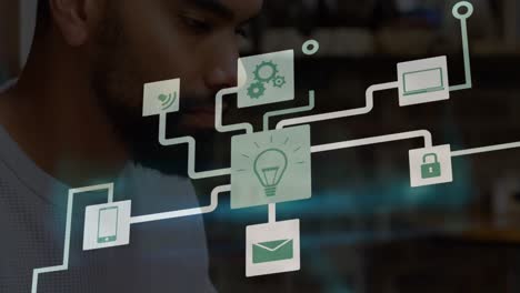 Animation of network of digital icons over african american man using laptop at office