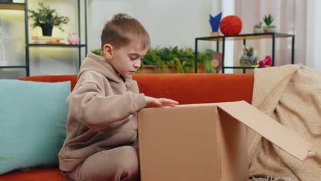 happy child boy shopper unpacking cardboard box delivery parcel online shopping purchase at home