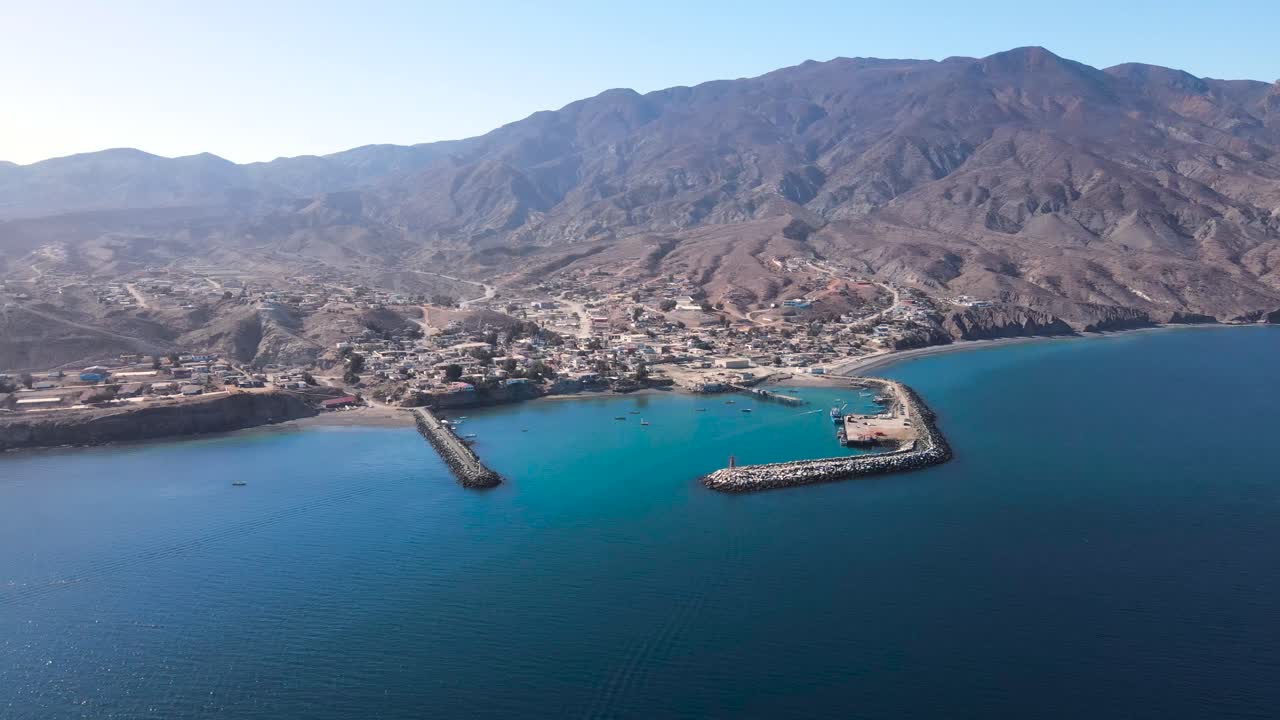 Scenic aerial establishment of Cedros Island harbor, featuring fishing boats docked along a vibrant coastline