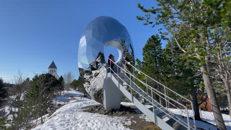 static shot of a tourist standing in the middel of the eye of the north in svolvaer park with blue sky and snow