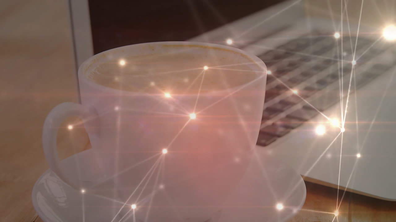 White ceramic coffee cup sitting on matching saucer, ambient light reflecting off laptop keyboard