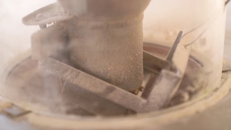 wheat grains falling from hopper to damsel through shoe of millstone